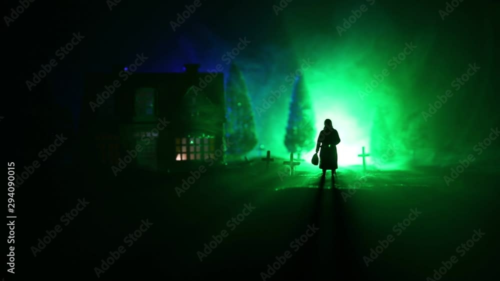 Silhouette of old woman with a cane walking at cemetery at night. Horror Halloween concept. Artwork decoration with light and fog. Selective focus Silhouette of old woman with a cane walking at cemetery at night. Horror Halloween concept. Artwork decoration with light and fog. Selective focus