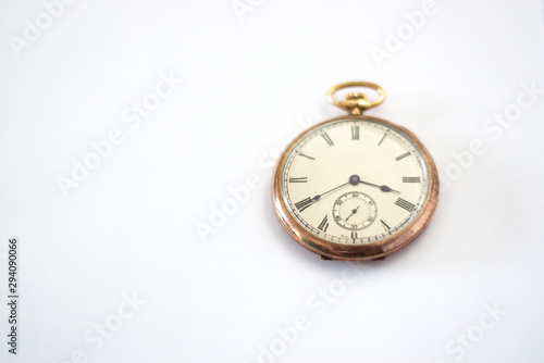 Gold pocket watch on white paper.