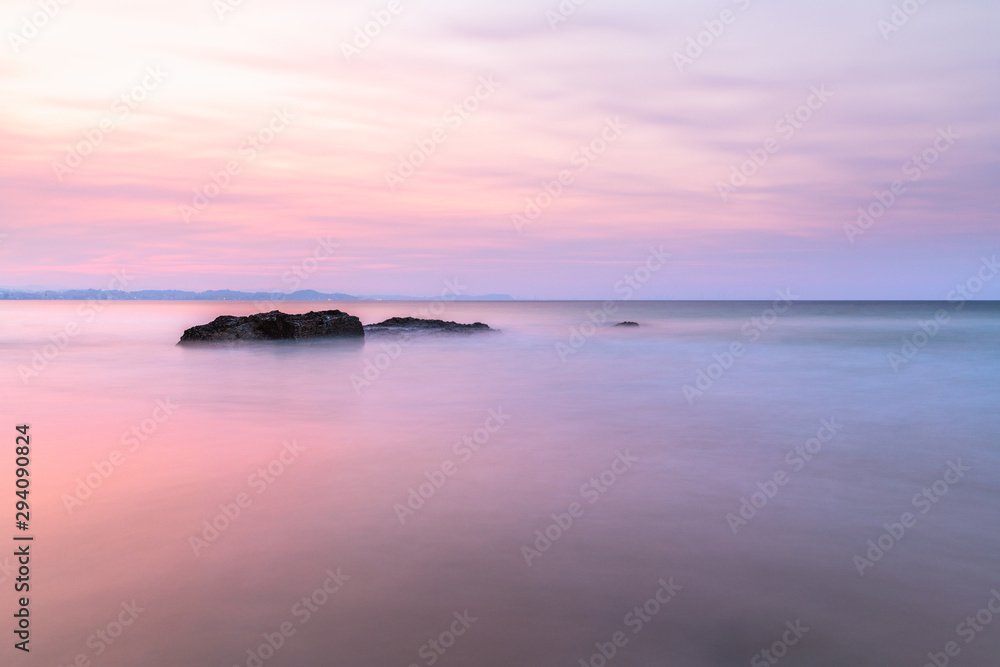 Long exposure of rocks in the ocean during sunset on a cloudy day in Snapper Rocks, Queensland, Australia.