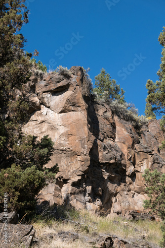 Rocky cliffs, trees and clear blue sky, vertical