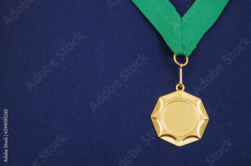 Gold medal with green ribbon on blue velveteen