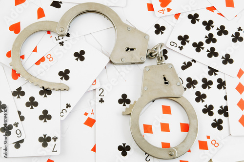 Handcuffs on cards background, gambling and law concept