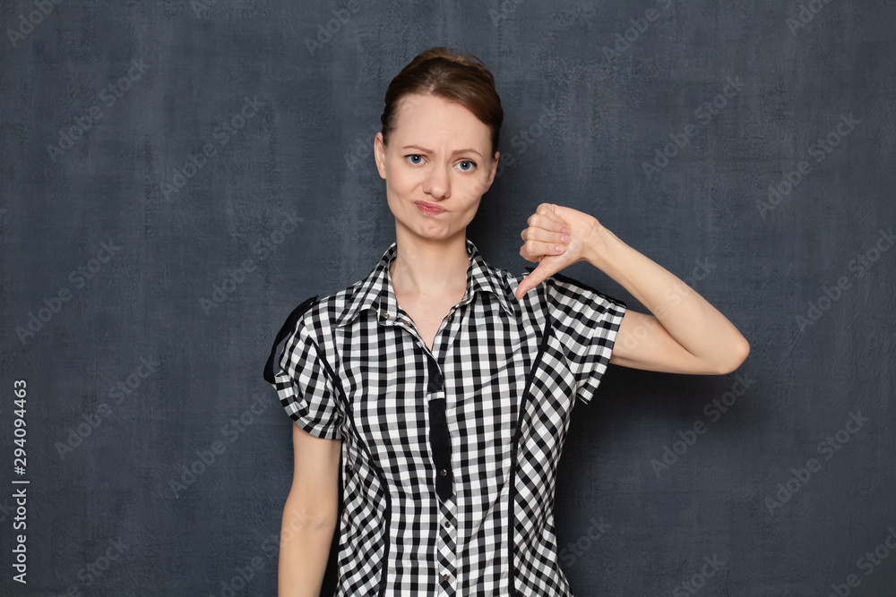 Portrait of disappointed young woman showing thumb down gesture Portrait of disappointed young woman showing thumb down gesture