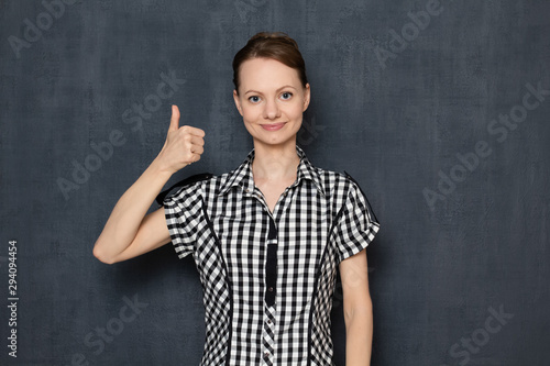 Portrait of happy young woman raising thumb up in like gesture