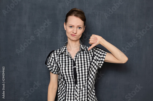 Portrait of disappointed young woman showing thumb down gesture © Andrei Korzhyts