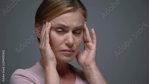 Worried woman massaging temples feeling terrible headache, migraine, pms