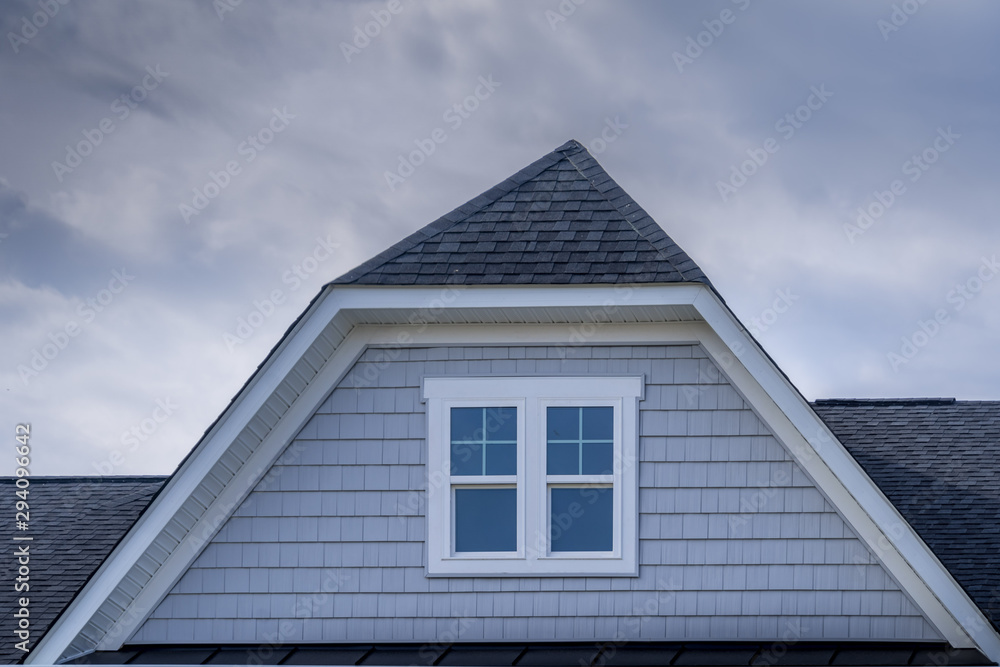 Gable with horizontal vinyl lap siding, double hung window with white frame on a pitched roof at an American luxury single family home neighborhood in the USA, shingle facade Gable with horizontal vinyl lap siding, double hung window with white frame on a pitched roof at an American luxury single family home neighborhood in the USA, shingle facade