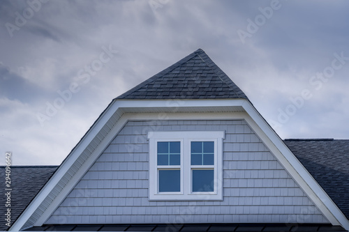 Gable with horizontal vinyl lap siding, double hung window with white frame on a pitched roof at an American luxury single family home neighborhood in the USA, shingle facade