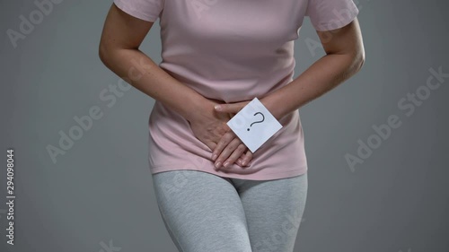 Lady with question mark sign on her hand touching belly, cystitis, dysmenorrhea