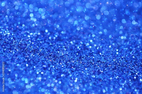 blue glitter with bokeh background.Christmas festive winter background.Shiny texture with highlights. Blue bokeh surface. sparkling shiny paper.Christmas holiday seasonal wallpaper