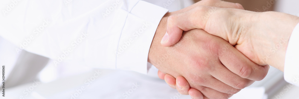 Doctor shake hand as hello with patient in office closeup. Welcoming friend introduction or thanks gesture consultation work thankful client talk team trust communication teamwork deal concept Doctor shake hand as hello with patient in office closeup. Welcoming friend introduction or thanks gesture consultation work thankful client talk team trust communication teamwork deal concept