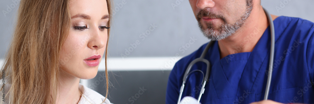 Smiling handsome doctor communicate with patient holding silver pen and showing pad. Physical agreement signature disease prevention consent sign 911 prescribe remedy healthy lifestyle concept