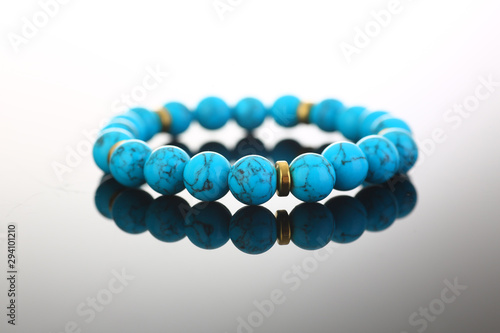 Bracelet of bijouterie jewelry made of turquoise and gold on a gray black background photo