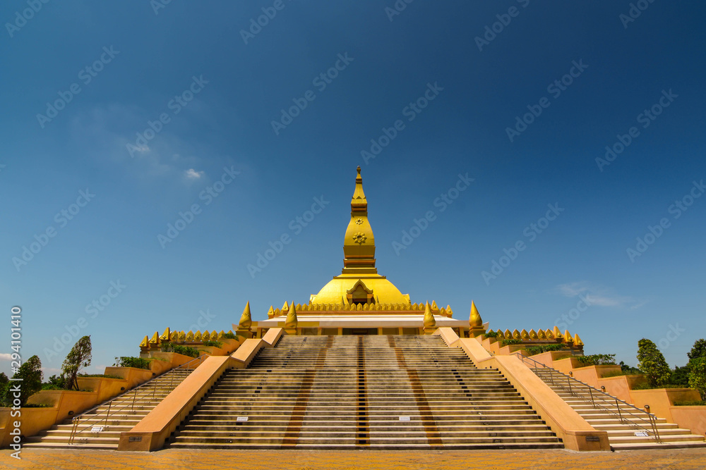 The golden pointed pagoda and the light at dusk. Buddhist tourist spots in Isan, Thailand, Southeast Asia