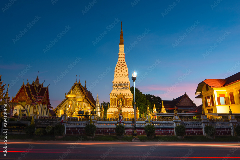 Fototapeta premium The golden pointed pagoda and the light at dusk. Buddhist tourist spots in Isan, Thailand, Southeast Asia