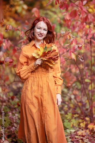 A bright girl with copper-colored hair. Beautiful autumn nature.