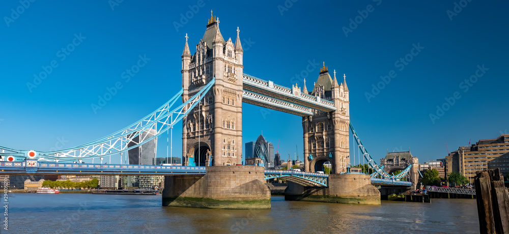 Fototapeta Panorama view of the Tower bridge over Thames river on a sunny day with the City Financial district skyscrapers and Tower of London in the background.