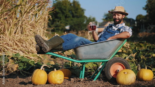 Farmer lying in a wheelbarrow resting and drink beer