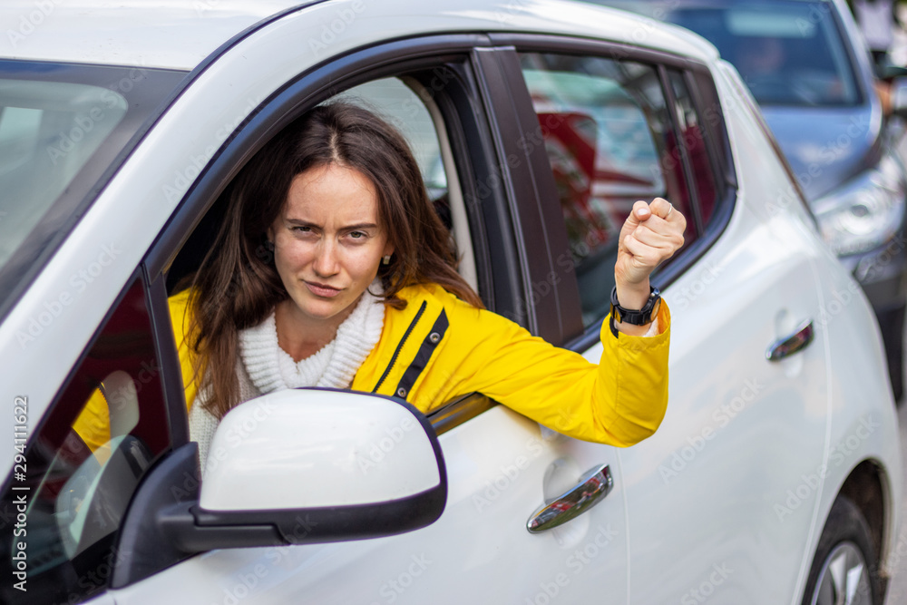 Angry woman driver threatens other drivers with a fist. Traffic jams concept.