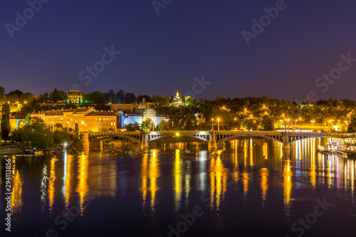 Night view of beautiful building at the bank and the reflection on the Vltava River, view from the Charles bridge, one of the famous historic building in Prague, Czech.