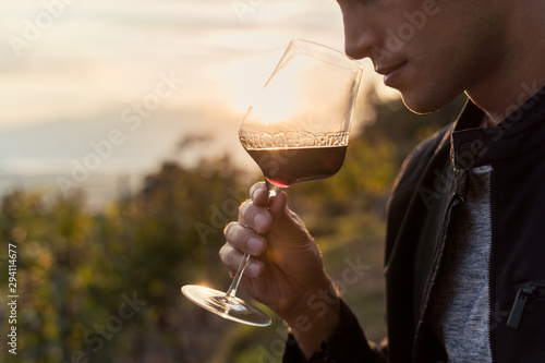 Fotografie close up of a young man tasting red wine in a vineyard during sunset