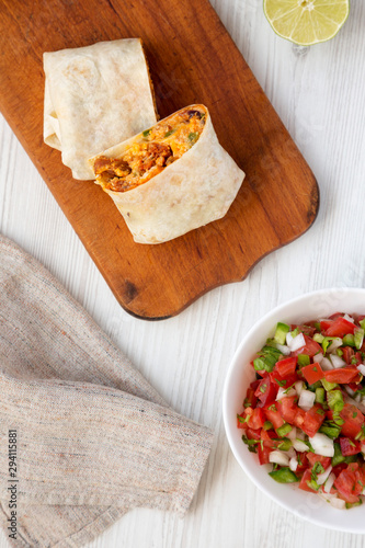 Homemade chorizo breakfast burritos with pico de gallo on a white wooden surface, overhead view. Flat lay, from above, top view.