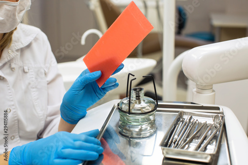 Female dentist holding spirit lamp (alcohol burner) and wax in dental clinic. Laboratory equipment, medicine and science, stomatology and healthcare concept.