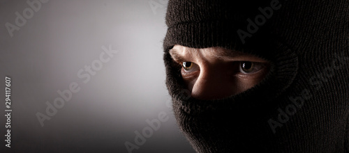 angry man in a balaclava on a dark background. photo
