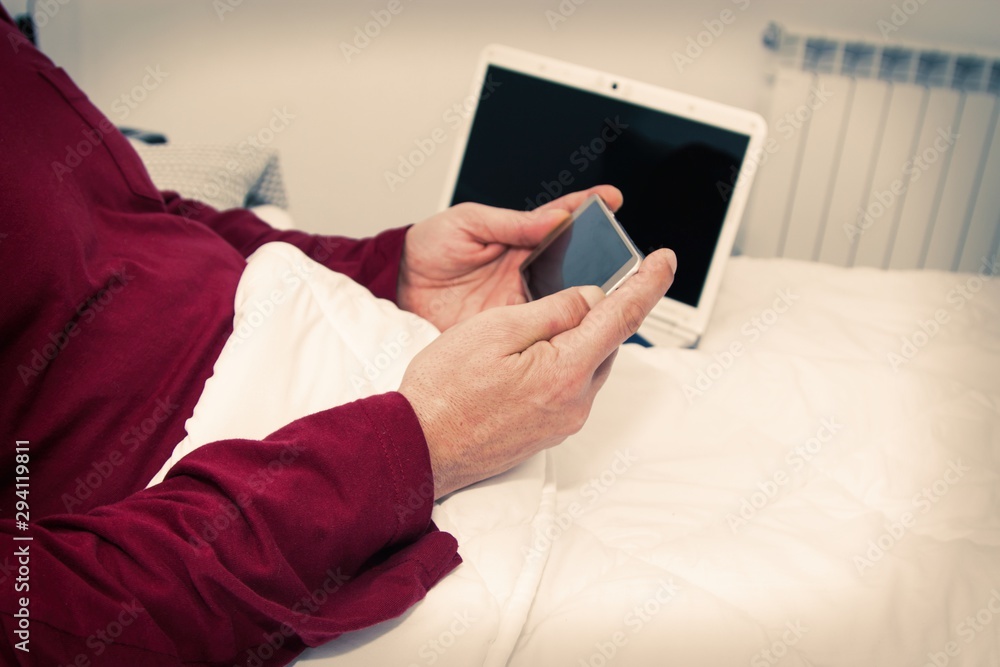 man lying in bed using mobile phone