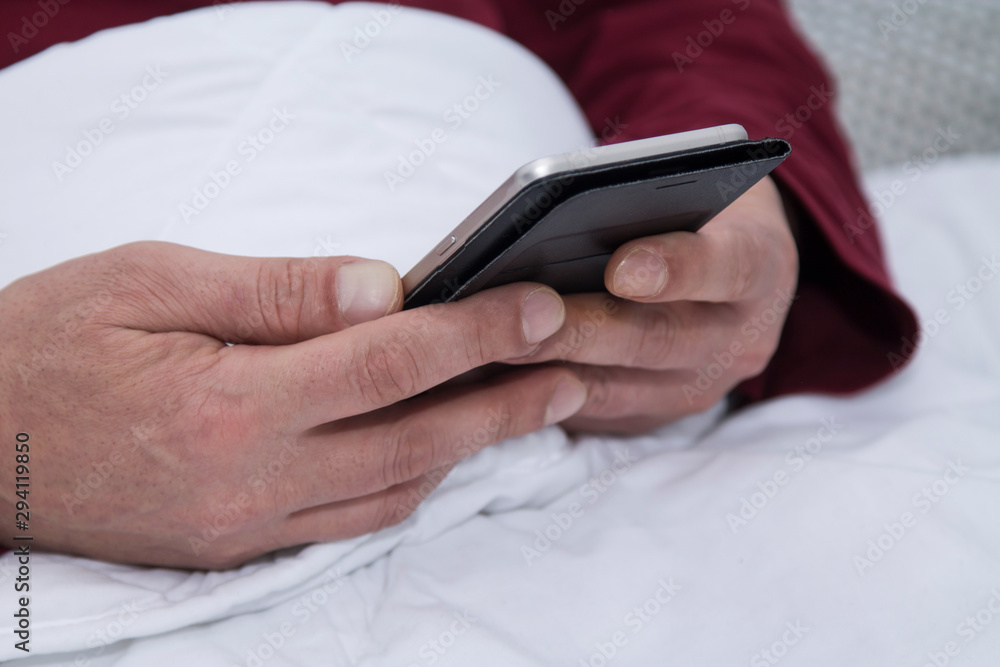 man lying in bed using his cellphone or smartphone man lying in bed using his cellphone or smartphone
