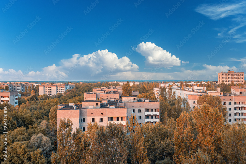 aerial view of the lost city of Pripyat wiht blue sky and clouds. a lot of empty concrete floors overgrown with trees. Pripyat is empty after the evacuation for 33 years after the accident 