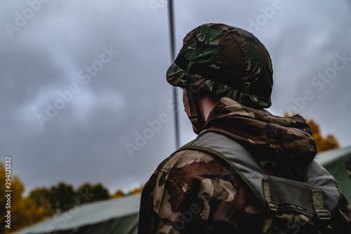 Soldier in the uniform. Back view. Low angle. Cloudy weather, autumn. Military concept © Dmitrii
