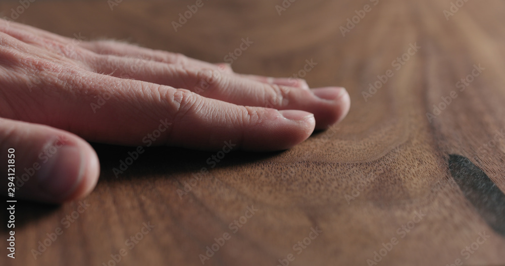 closeup man hand check oiled black walnut surface closeup man hand check oiled black walnut surface
