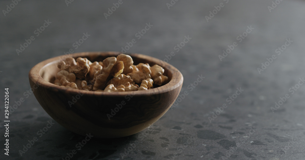 walnut kernels in wooden bowl on terrazzo countertop walnut kernels in wooden bowl on terrazzo countertop