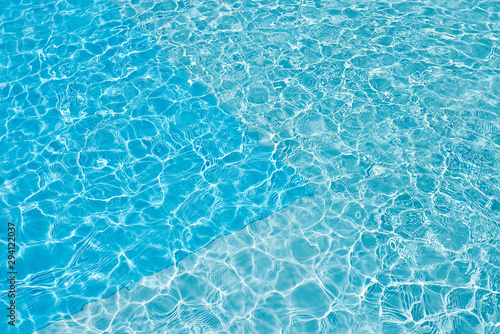 Background of water in blue swimming pool  water surface with a sun reflection