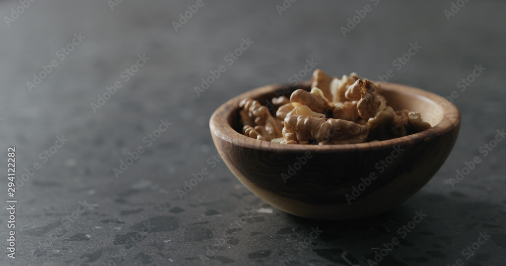 walnut kernels in wooden bowl on terrazzo countertop walnut kernels in wooden bowl on terrazzo countertop