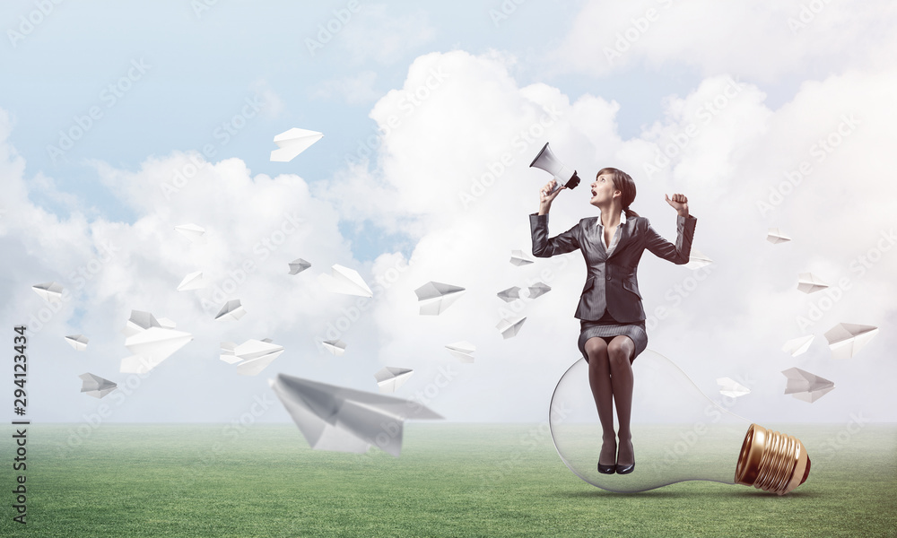Woman with megaphone sitting on big light bulb Woman with megaphone sitting on big light bulb