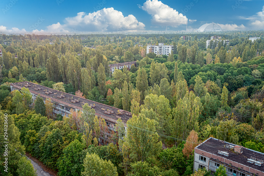 aerial view of the lost city of Pripyat wiht blue sky and clouds. a lot of empty concrete floors overgrown with trees. Pripyat is empty after the evacuation for 33 years after the accident 