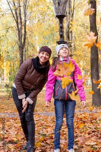 happy family playing with fallen leaves in autumn park