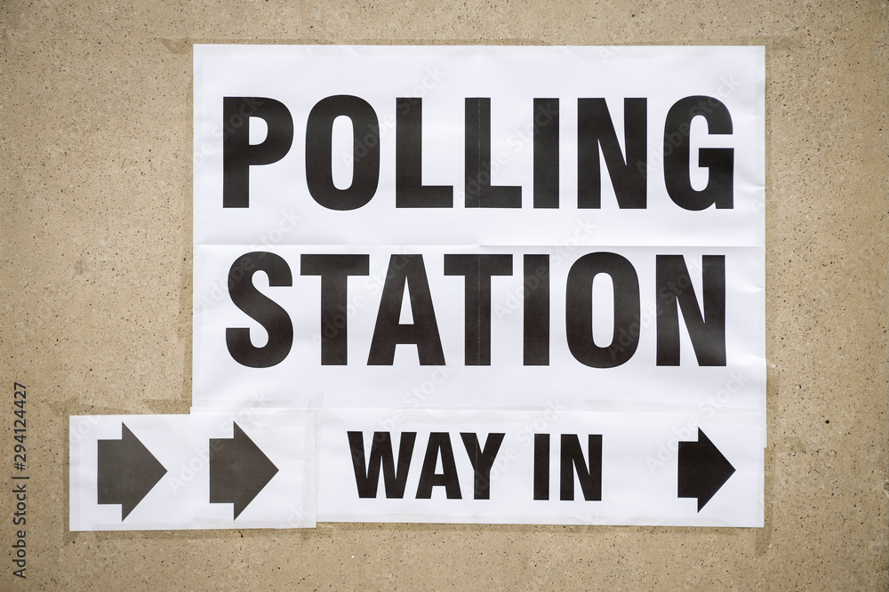 British election polling station entrance sign hanging with arrows pointing the way in on a street in London, UK British election polling station entrance sign hanging with arrows pointing the way in on a street in London, UK