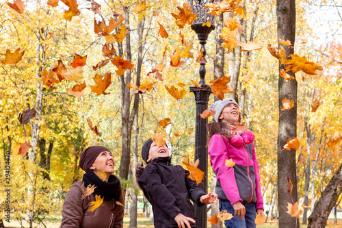 happy family playing with fallen leaves in autumn park