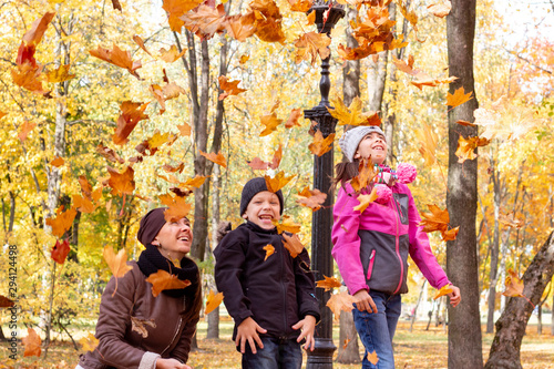 happy family playing with fallen leaves in autumn park