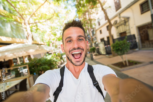 Handsome man takes a selfie walking in the city photo