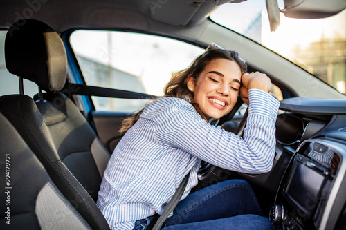 фотографія Young and cheerful woman enjoying new car hugging steering wheel sitting inside