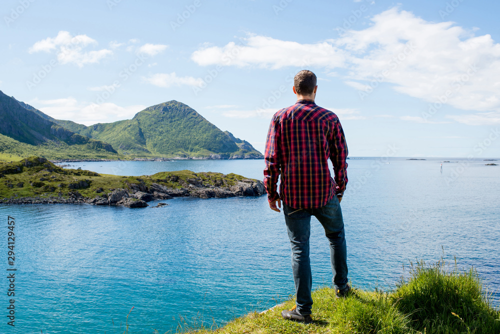 Fototapeta premium A men enjoy the scenic nature. Northern beauty panoramic view. Fjord, ocean and mountain landscape. Travel, adventure. Sense of freedom, relax lifestyle. Explore North Norway. Summer in Scandinavia