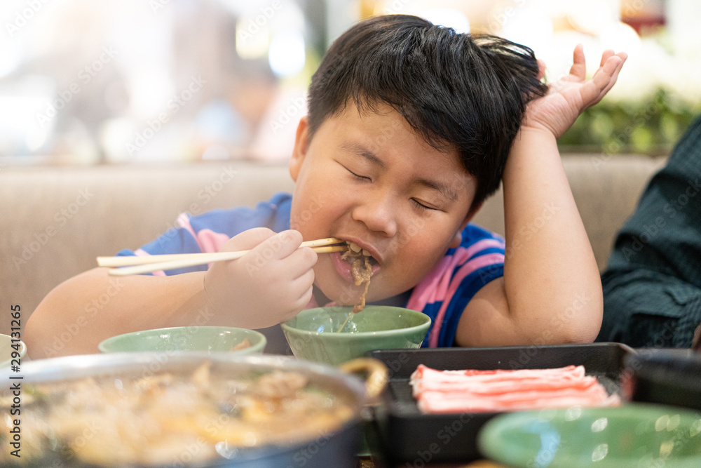 A kid is eating deliciously boiled beef with sukiyaki soup in a shabu pot at the Japanese restaurant. A kid is eating deliciously boiled beef with sukiyaki soup in a shabu pot at the Japanese restaurant.