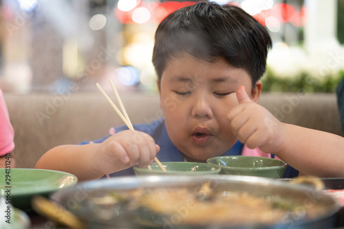 A kid is eating deliciously boiled beef with sukiyaki soup in a shabu pot at the Japanese restaurant.