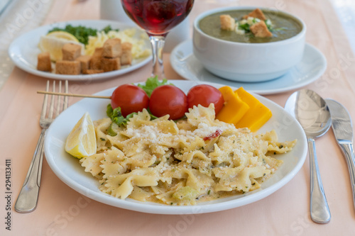 Pasta farfalle with cherry tomato and cheese in white plate, closeup
