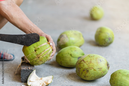 Green fresh coconut peeling and shelling with heavy chop knife for juice.