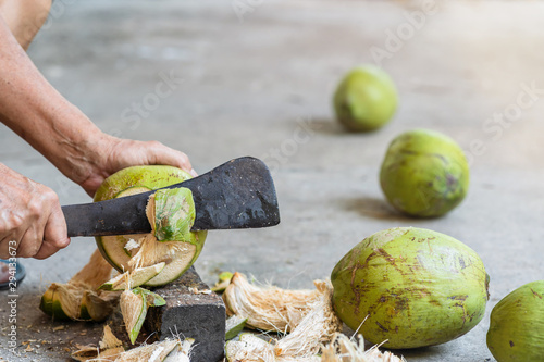 Green fresh coconut peeling and shelling with heavy chop knife for juice.